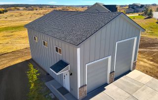 Detached gray pole barn garage with paved vehicle access and open rural land in Douglas County, Colorado