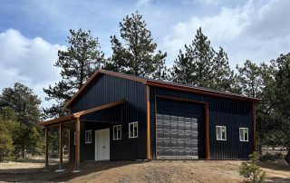 Colorado pole barn with dark metal roofing and siding on a wooded property in Teller County