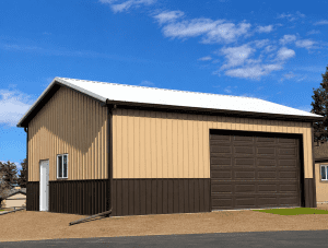 Beige and brown metal garage or storage building with a white door, large brown overhead door, and a white roof, situated on gravel under a blue sky.