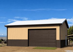 A tan and brown metal garage building with a large dark brown roll-up door, set on gravel ground under a clear blue sky.